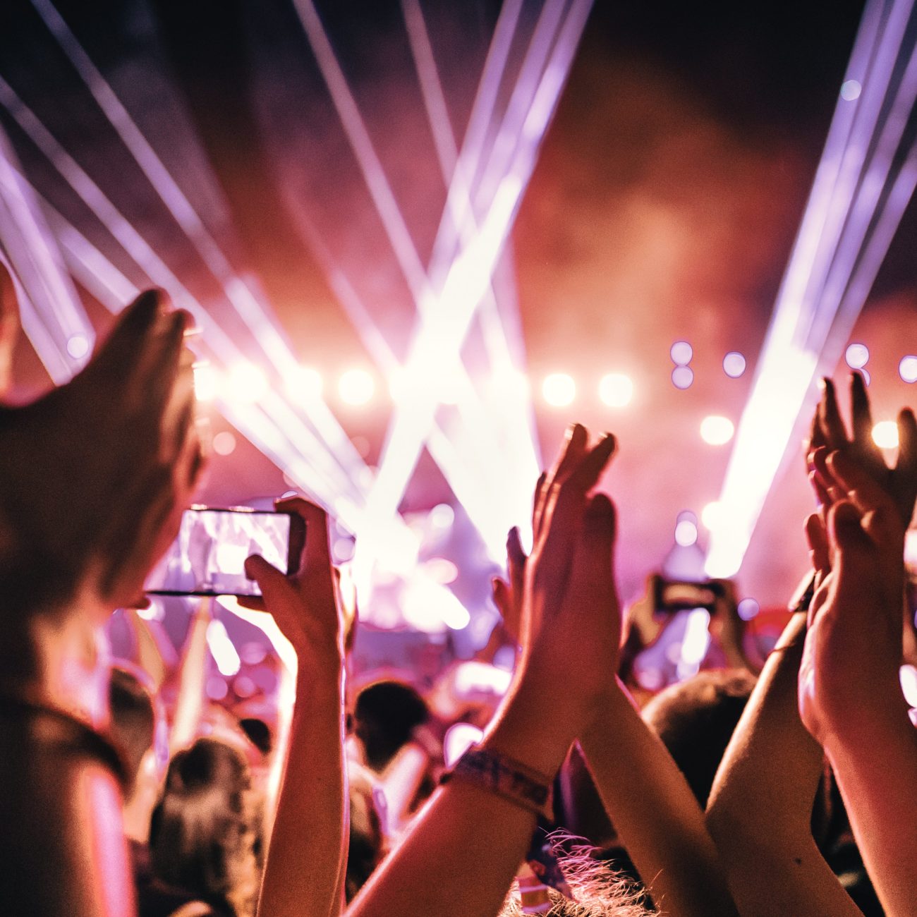 Rear view of large group of people enjoying a concert performance.  People in foreground are released.