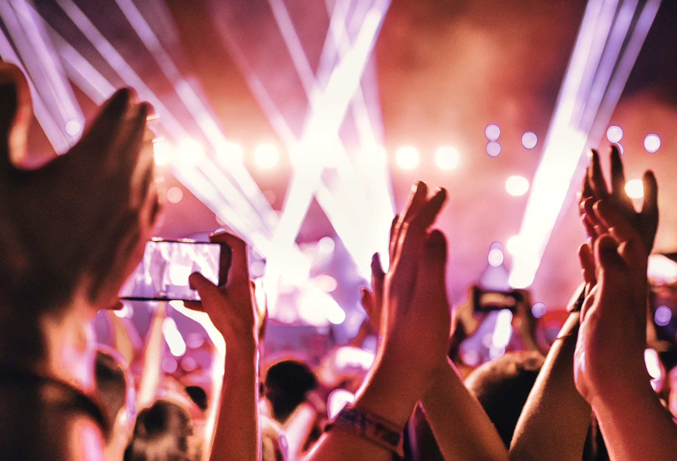 Rear view of large group of people enjoying a concert performance.  People in foreground are released.